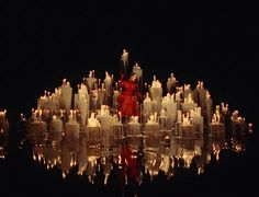 a woman in a red dress surrounded by candles