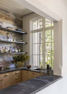 a kitchen with marble counter tops and open shelves in front of a window that looks out onto the outdoors