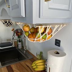 some fruit is in a hammock hanging from the kitchen wall above a sink