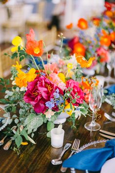 the table is set with colorful flowers and silverware