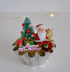 a christmas ornament sitting on top of a cupcake with a tree in it