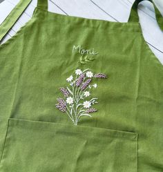 a green apron with flowers embroidered on it