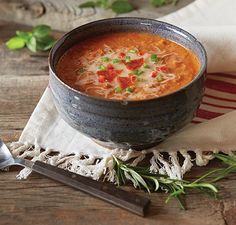 a bowl of soup is sitting on a table next to a spoon and napkins