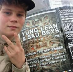 a young boy wearing a hat standing in front of a sign