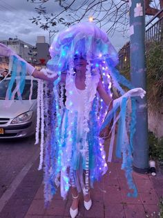 a woman dressed in blue and white is standing on the sidewalk with her arms out