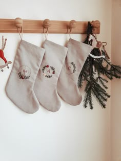 three christmas stockings hanging on the wall next to a wreath and pine cone ornament