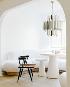 a living room with white furniture and a chandelier