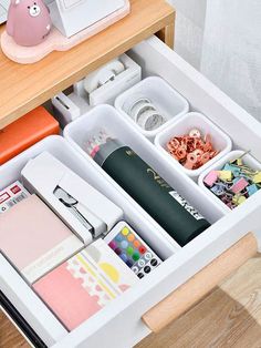 an organized drawer is shown with various items in the drawers, including pens and magnets