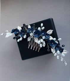 a hair comb with blue and white flowers on it's headpiece, against a gray background