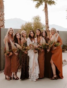 a group of women standing next to each other wearing dresses and holding bouquets in their hands