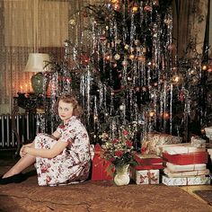 a woman sitting in front of a christmas tree