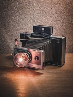 an old fashioned camera sitting on top of a wooden table