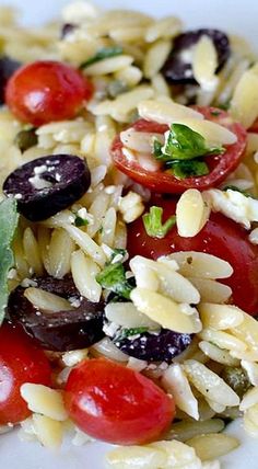 a white plate topped with rice, tomatoes and olives