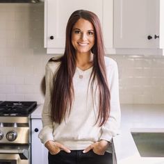 a woman is standing in the kitchen with her hands on her hips and looking at the camera