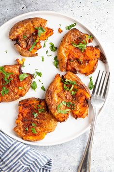 four pieces of cooked chicken on a white plate with a fork and knife next to it