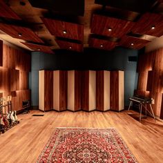 an empty room with wooden paneling and guitars on the floor in front of it