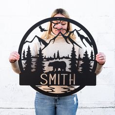 a woman holding up a sign that says smith with an image of a bear in the woods