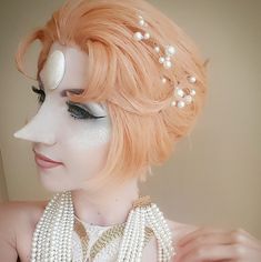 a woman with orange hair and pearls on her head wearing a white dress, necklace and earrings