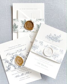 three wedding cards with wax stamp on them, one is white and the other is blue