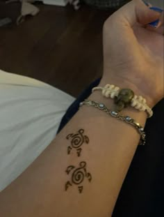 a woman's arm with a tattoo on it and a beaded bracelet around her wrist