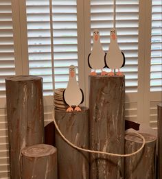 three penguins are standing on top of logs with paper cutouts attached to them,