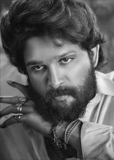 a black and white photo of a man with a beard holding his hand up to his face