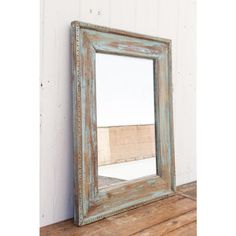 an old mirror sitting on top of a wooden table