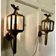 two old fashioned wall lights on the side of a white door with an eagle decoration