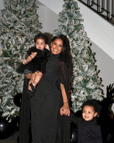 a woman and two children standing in front of a christmas tree