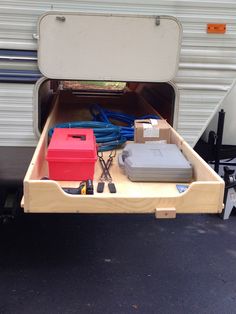 the back end of a camper trailer with its storage compartment open and tools in it