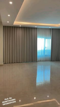 an empty living room with large windows and curtains