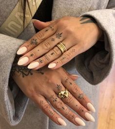 two hands with different tattoos on them and one has a gold ring in the middle