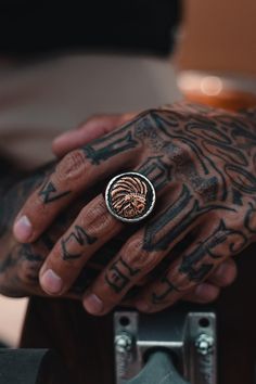 a tattooed hand with a ring on it