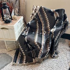 a blanket sitting on top of a table next to a lamp and a white dresser