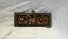 an old wooden box that has been decorated with gold and red designs on it, sitting on a white sheet