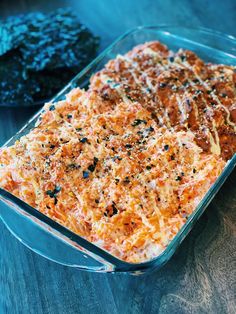 a casserole dish with meat and cheese in it on a table next to some seaweed