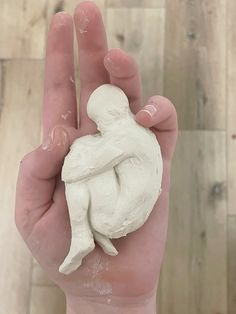 a hand holding a small white object in it's palm