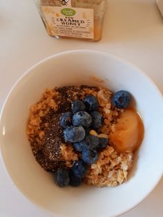 a bowl filled with oatmeal and blueberries next to a jar of honey