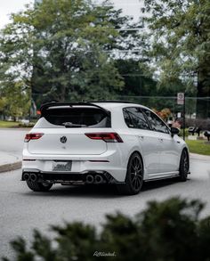 the rear end of a white car parked on the street