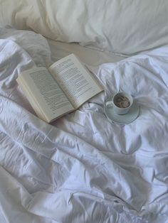 an open book and cup of coffee on a bed