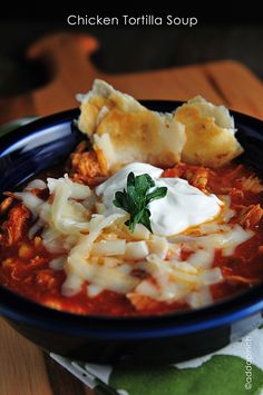 a bowl of chicken tortilla soup with sour cream and parmesan cheese