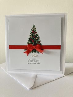 a christmas card with a red ribbon and a small tree on the front that says merry christmas