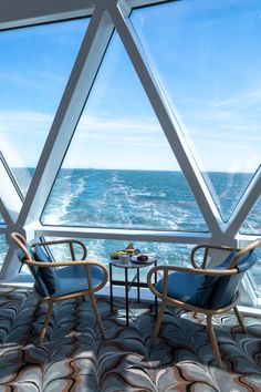 two chairs sitting next to each other in front of a window overlooking the ocean on a cruise ship