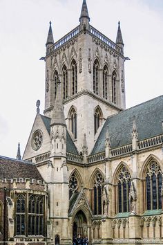 an old building with many windows and people walking around it in front of the church