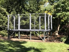 a small trampoline in the middle of a grassy area next to some trees