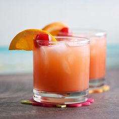 two glasses filled with orange juice and garnished with an orange slice on the rim