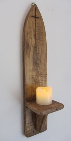 a wooden shelf with a lit candle on it and a cross hanging from the wall