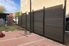 a large truck parked next to a tall fence on top of a brick sidewalk in front of a building