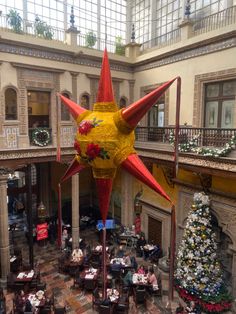 a large christmas star in the middle of a building with tables and chairs around it