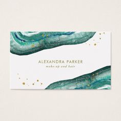 a white business card with gold foil on it and some green plants in the background